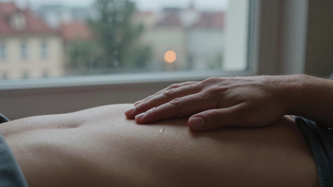 Ruka ležící na břiše s olejem leskne se v měkkém světle.